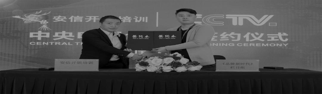 CCTV 签约仪式现场，两人在红台前握手并出示签约文件夹